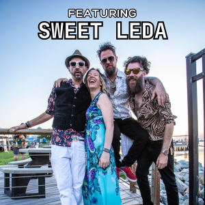 Four members of the band Sweet Leda pose together outside on a dock. Two men stand on either side, a woman in a patterned dress smiles in the center, and another man leans on her, all laughing under a clear sky. Text reads "Featuring Sweet Leda.